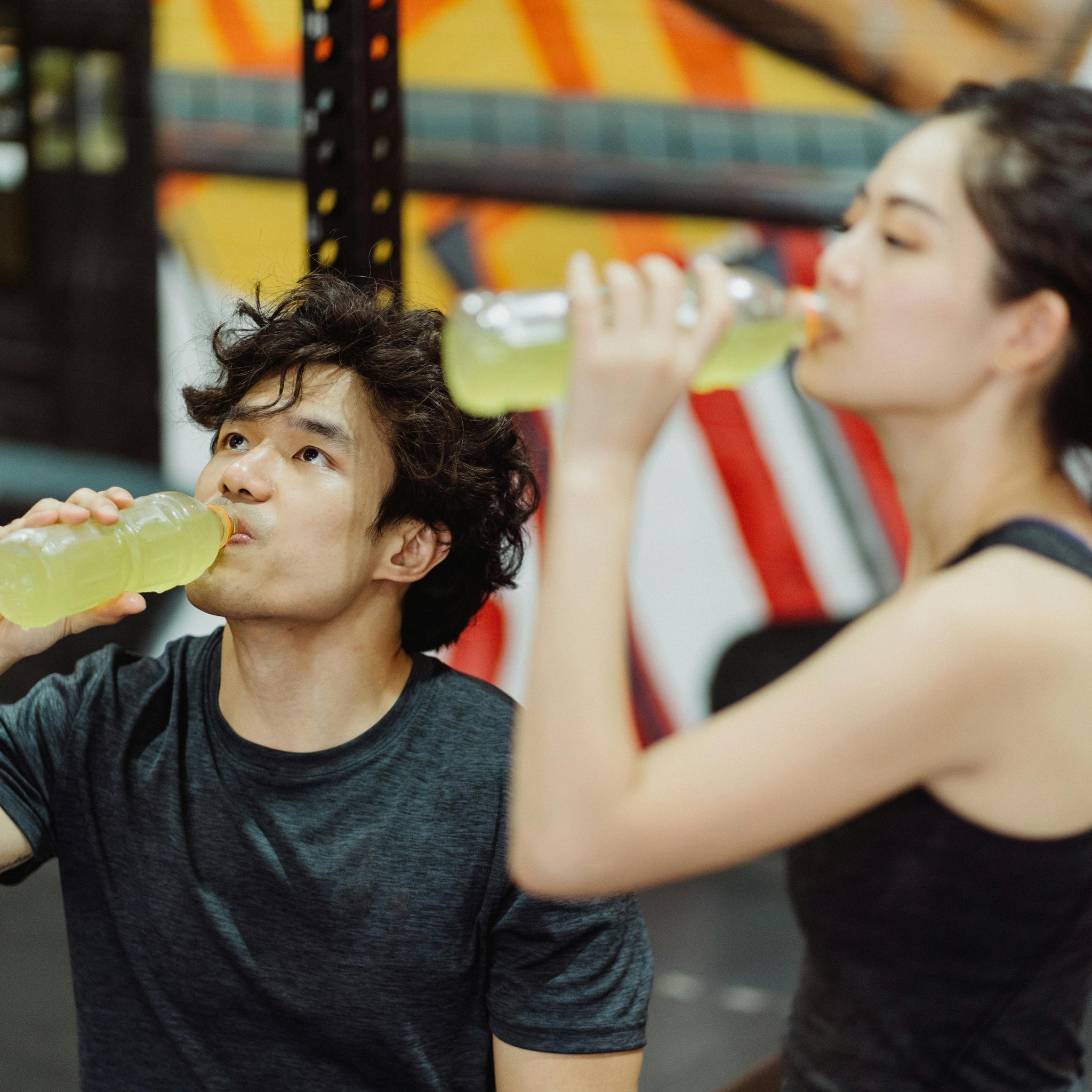 Zwei Menschen trinken nach dem Sport aus einer Flasche